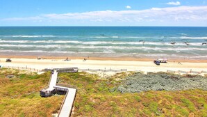 Una playa con una pasarela de madera que lleva a un edificio frente al mar.