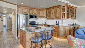 Una cocina amplia con armarios de madera, un refrigerador de acero inoxidable, un microondas y una isla grande con taburetes de bar.