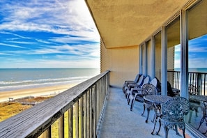 A balcony with a view of the beach and ocean.