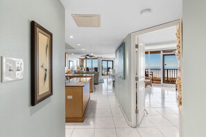 Enter a stylish hallway leading to a balcony with ocean views, featuring a kitchen, dining, and seating areas.