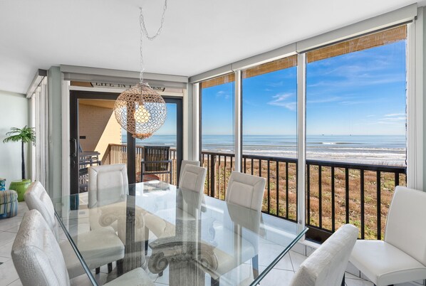 Enjoy a meal at the glass dining table surrounded by comfortable chairs, with a stunning ocean view.