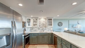 Una cocina moderna con un refrigerador de acero inoxidable, horno empotrado y una isla grande con pileta.