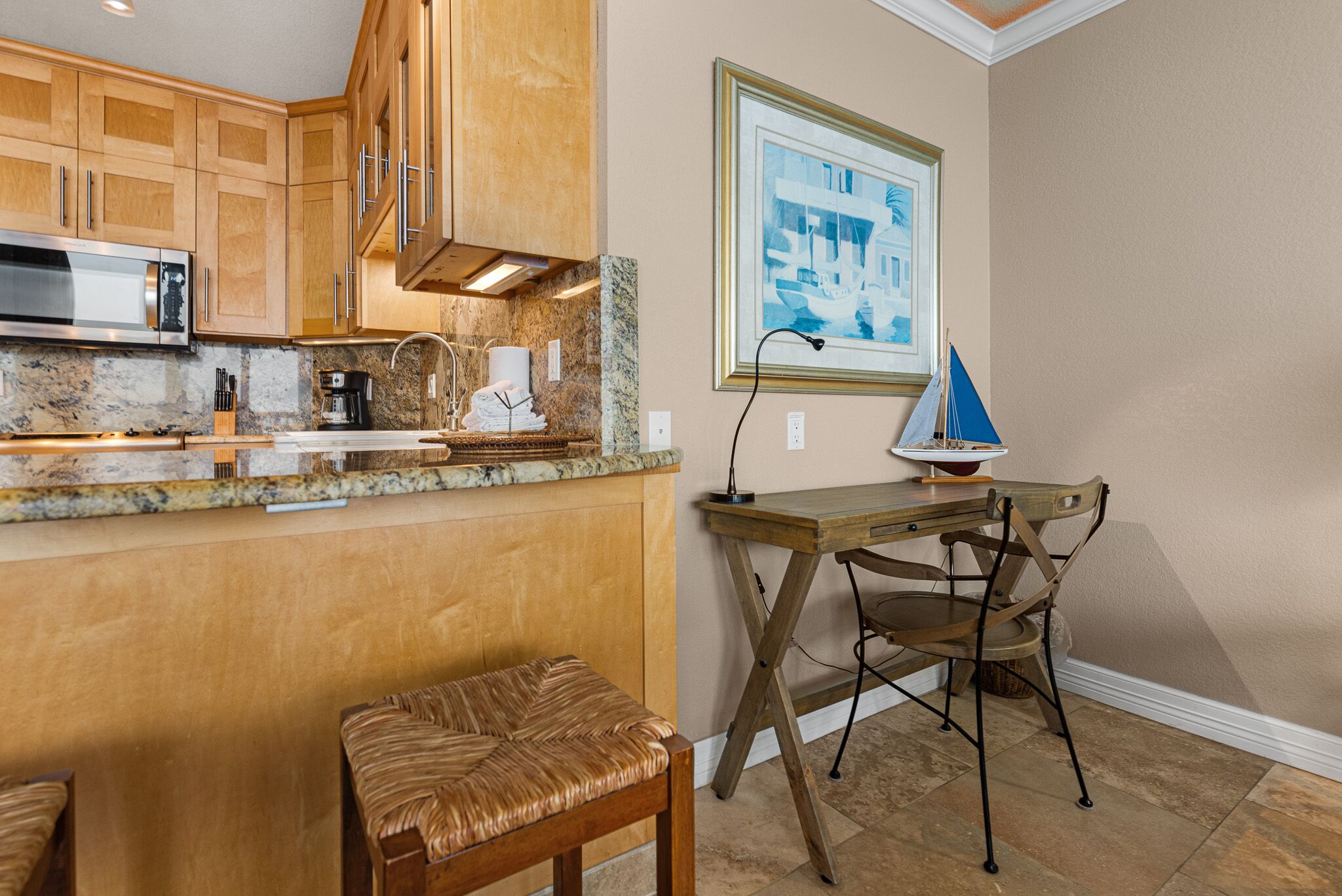 A kitchen with wooden cabinets, a microwave, a coffee maker, and a framed picture on the wall.