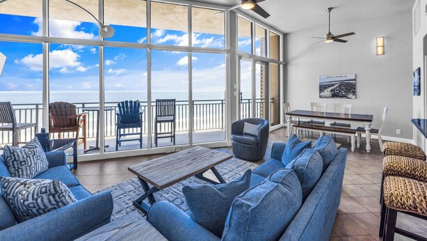 A spacious balcony with a view of the ocean, furnished with a sofa, chairs, and a dining table.