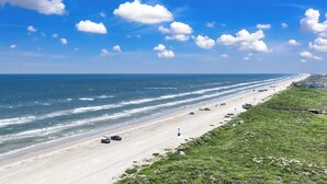 A coastal beach scene with a clear sky and ocean waves.