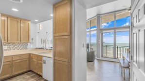 A modern kitchen with wooden cabinets and a view to a balcony with a railing and a table.