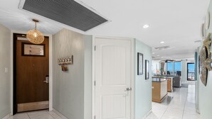 A hallway with a wooden door, a white door, and a kitchen area with a counter and sink.