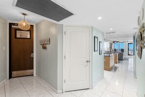 A hallway with a wooden door, a white door, and a kitchen area with a counter and sink.