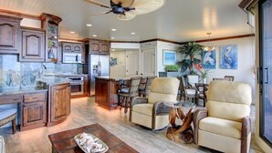 A spacious living area with a kitchen, dining area, and seating with a ceiling fan. - Sea Gull #802: Beachfront 2 Bedroom 2 Bathroom With Spectacular Views and 24 Hour Management (Port Aransas)