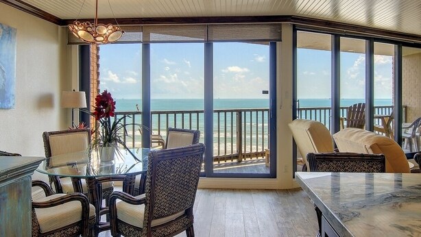 A spacious balcony with a clear view of the ocean, furnished with chairs and a glass table. - Sea Gull #802: Beachfront 2 Bedroom 2 Bathroom With Spectacular Views and 24 Hour Management (Port Aransas)