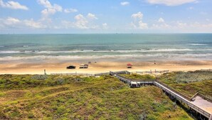 A beach with a wooden boardwalk, a lifeguard tower, and a sandy beach area. - Sea Gull #802: Beachfront 2 Bedroom 2 Bathroom With Spectacular Views and 24 Hour Management (Port Aransas)
