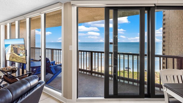 Ein Balkon mit Blick auf den Ozean, einem Fernseher und Gartenmöbeln.