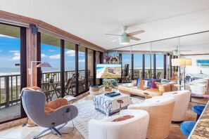 Ein geräumiger Balkon mit Meerblick, ausgestattet mit einer Couch, Stühlen und einem Esstisch.