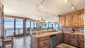 Una cocina amplia con armarios de madera, lavavajillas y una isla grande. Ofrece vistas al océano a través de amplios ventanales.