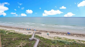A beach with a wooden boardwalk leading to the shore, clear blue sky, and calm sea. - Sea Gull #906: Beachfront 2 Bedroom 2 Bathroom With Spectacular Views and 24 Hour Management (Port Aransas)