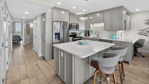 A modern kitchen with a central island, stainless steel appliances, and a herringbone-patterned backsplash. - Sea Gull #906: Beachfront 2 Bedroom 2 Bathroom With Spectacular Views and 24 Hour Management (Port Aransas)