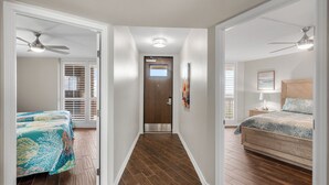 A bedroom with a bed, a nightstand, a ceiling fan, and a door leading to another room. - Sea Gull #609: Beachfront 2 Bedroom 2 Bathroom With Spectacular Views and 24 Hour Management (Port Aransas)