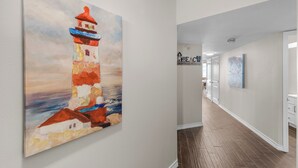 A hallway with a painting of a lighthouse, a sign reading "BEACON," and a door leading to a room. - Sea Gull #609: Beachfront 2 Bedroom 2 Bathroom With Spectacular Views and 24 Hour Management (Port Aransas)