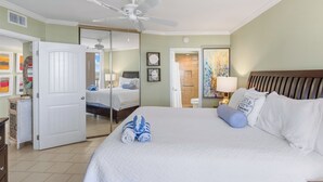Habitación de hotel con una cama grande, ventilador de techo, baño con ducha y vista al exterior.