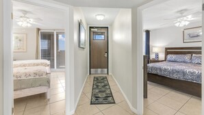 A hallway leading to a bedroom with a bed, a nightstand, and a ceiling fan. - Sea Gull #509: Beachfront 2 Bedroom 2 Bathroom With Spectacular Views and 24 Hour Management (Port Aransas)