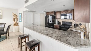 A modern kitchen with granite countertops, stainless steel appliances, and wooden cabinetry. - Sea Gull #509: Beachfront 2 Bedroom 2 Bathroom With Spectacular Views and 24 Hour Management (Port Aransas)