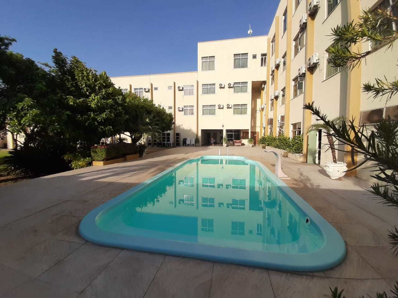Piscina cercada por um edifício com várias janelas e aparelhos de ar condicionado.