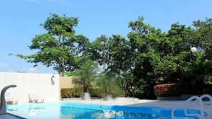 Una piscina con sillas de descanso y una pared blanca.