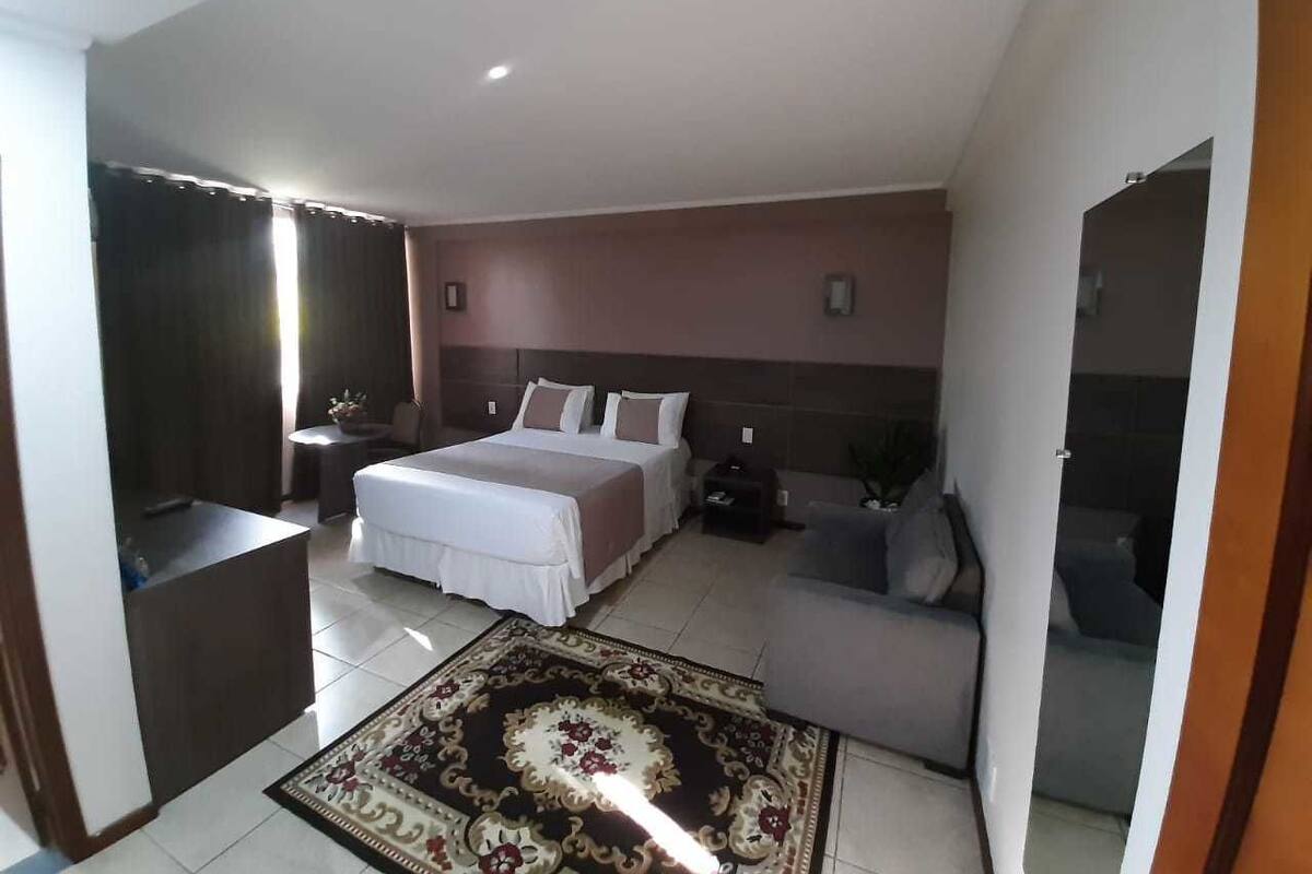 A bedroom with a bed, a sofa, a nightstand, and a small table.