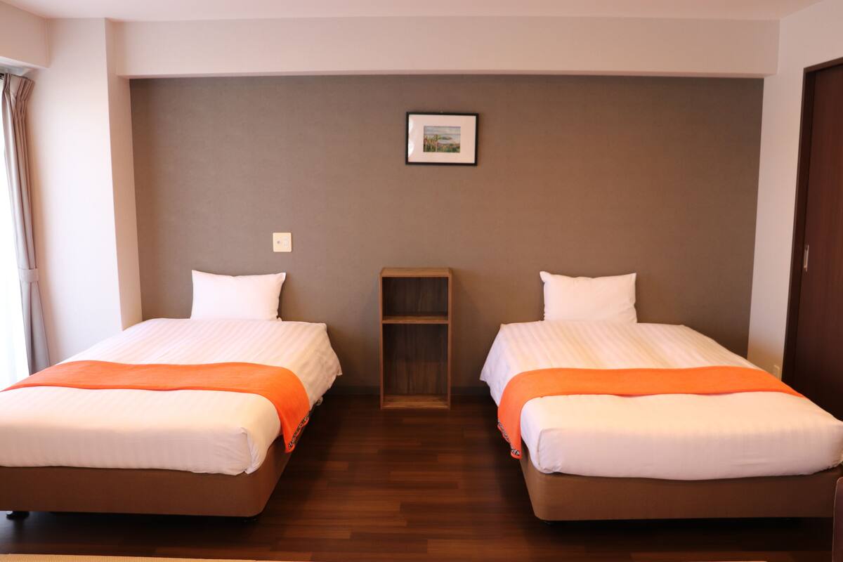 A hotel room with two beds, a wooden shelf, and a framed picture on the wall.