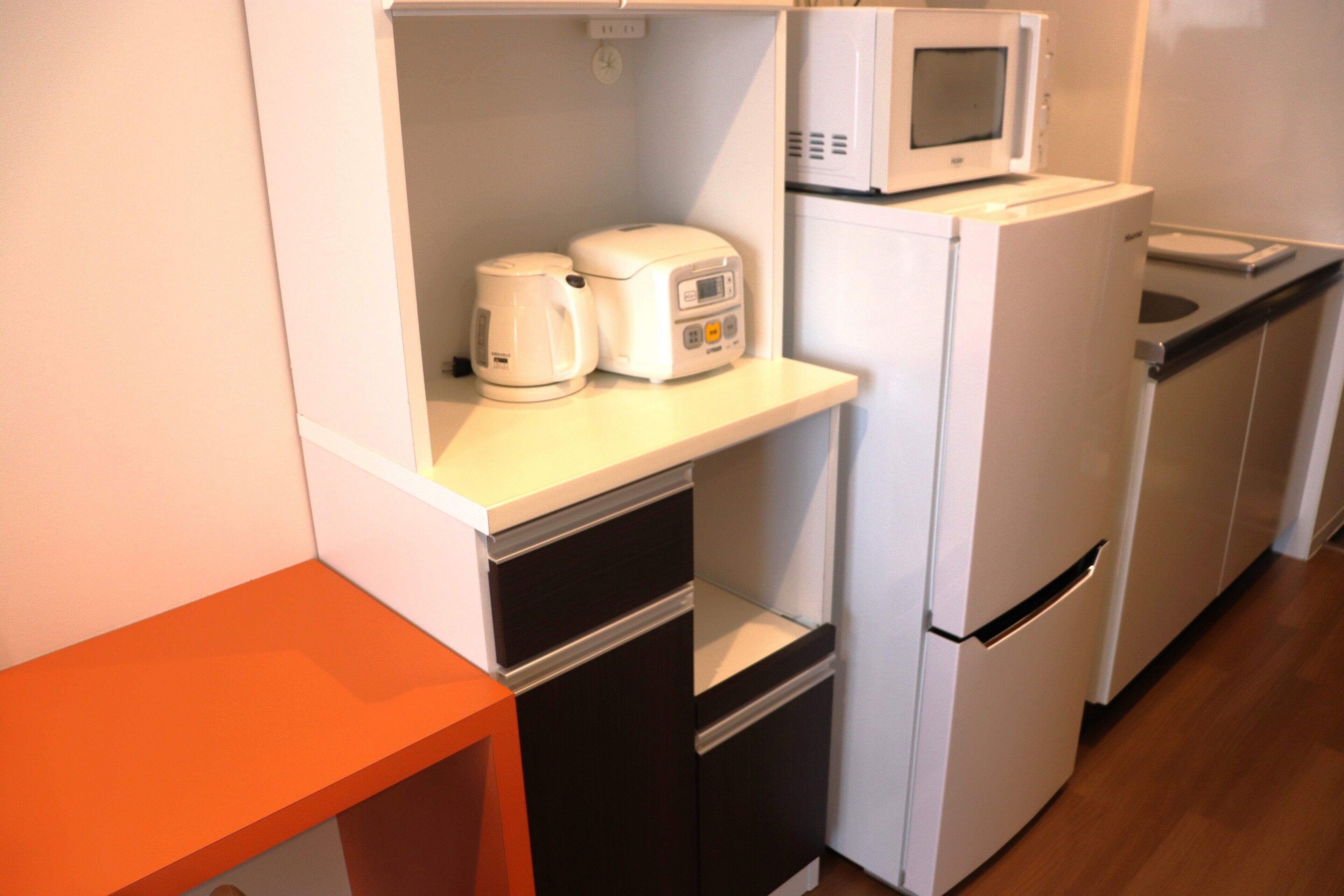 A compact kitchenette with a microwave, coffee maker, and refrigerator.
