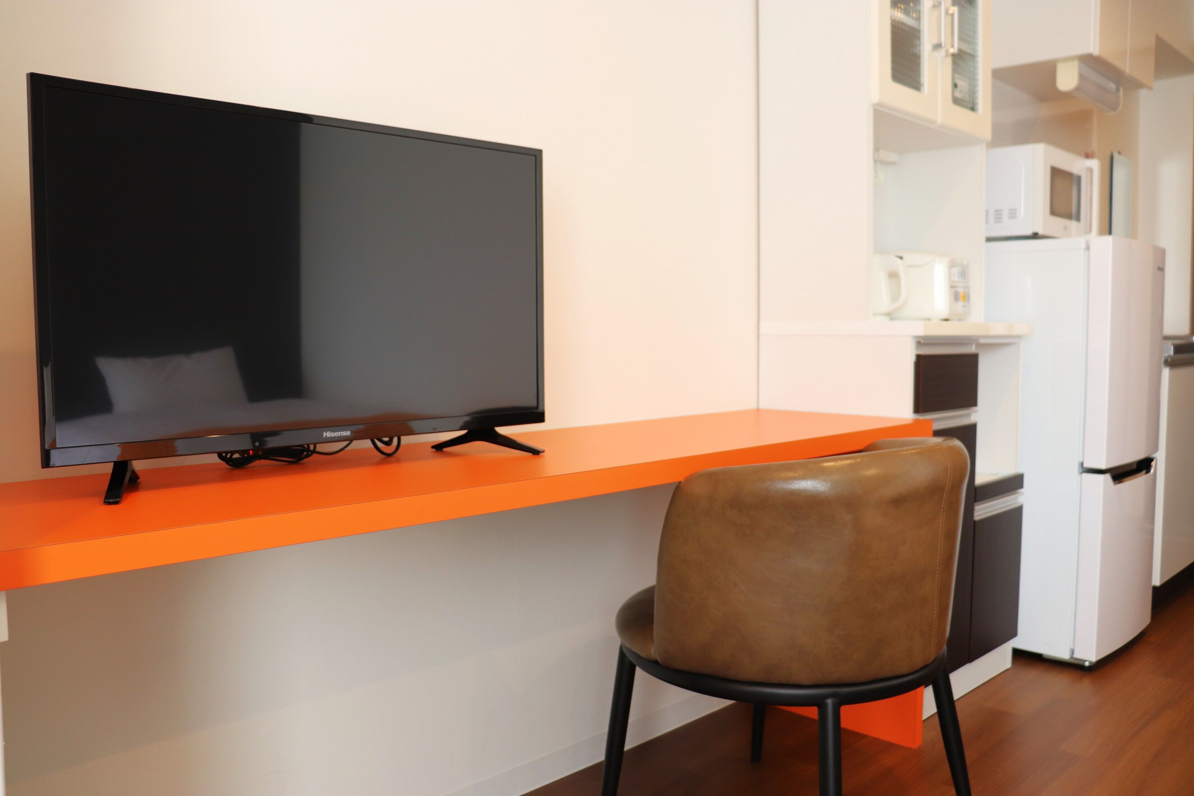 A modern kitchen with a flat-screen TV, a microwave, and a refrigerator.