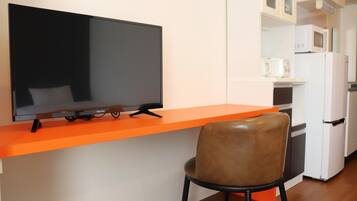 A modern kitchen with a flat-screen TV, a microwave, and a refrigerator.