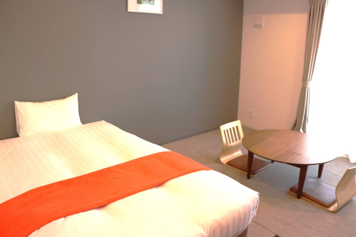 A hotel room with a bed, a small table, and a chair.