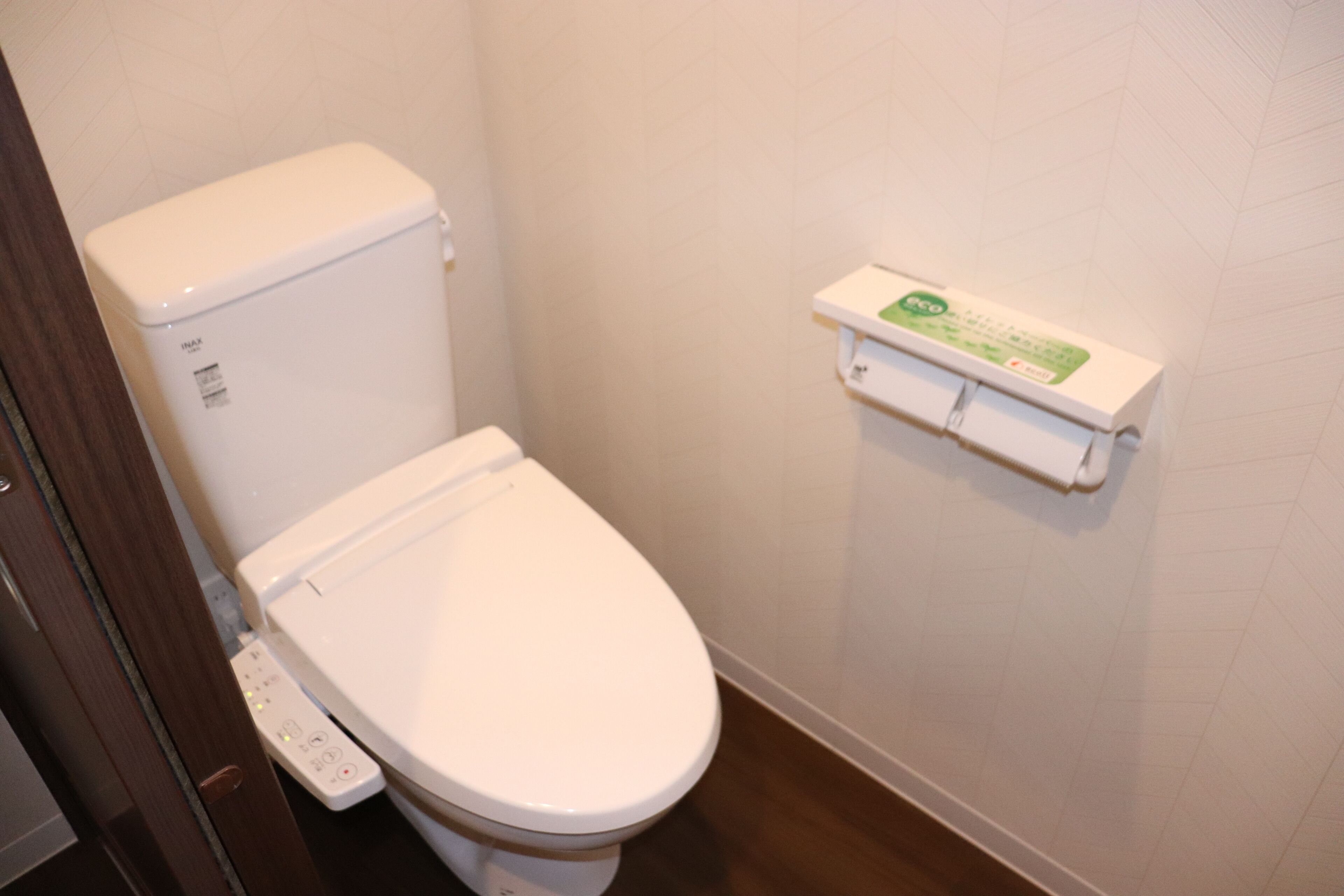 Inodoro con panel de control y dispensador de papel higiénico en la pared.