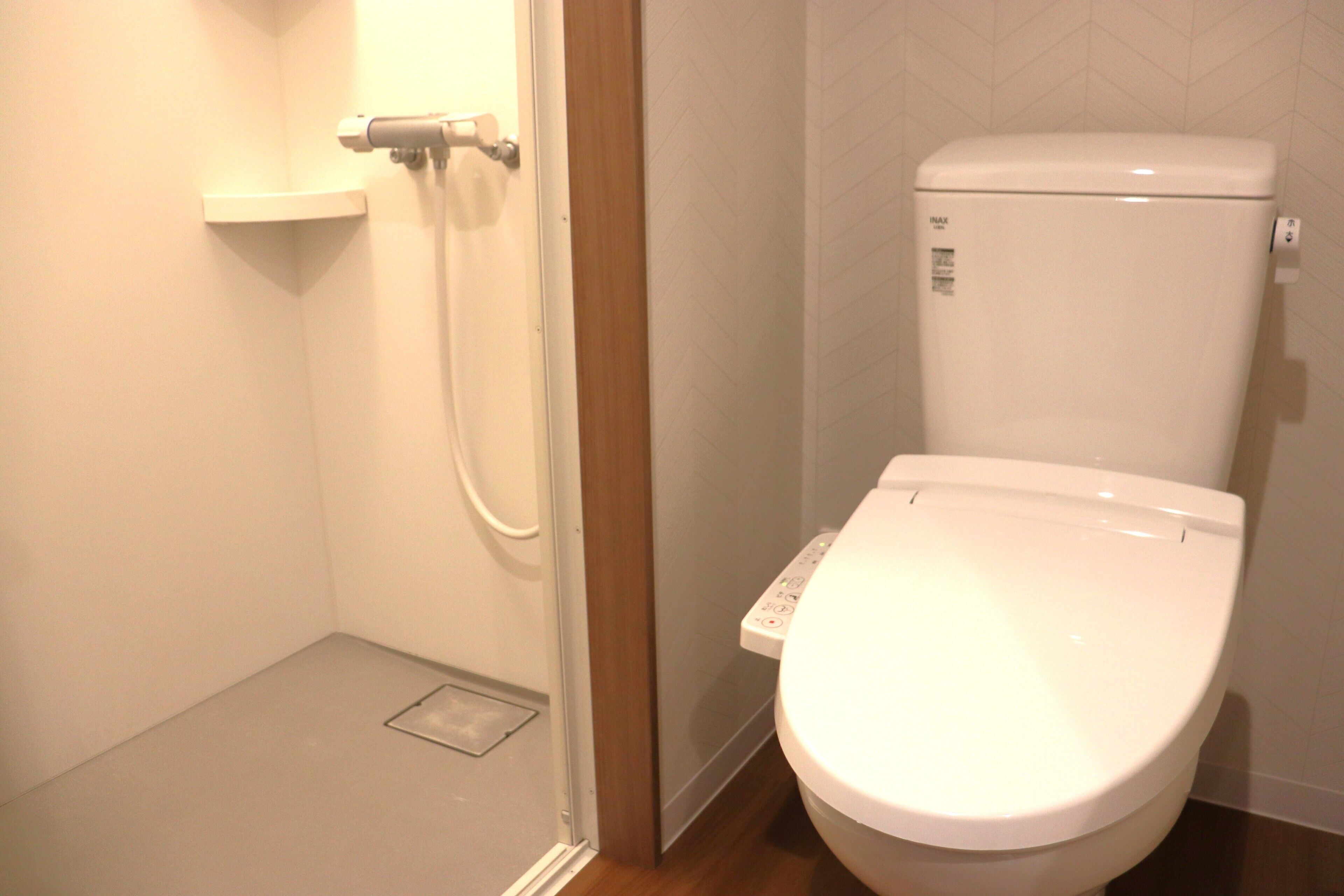 A bathroom with a white toilet, a shower area, and a wooden door.