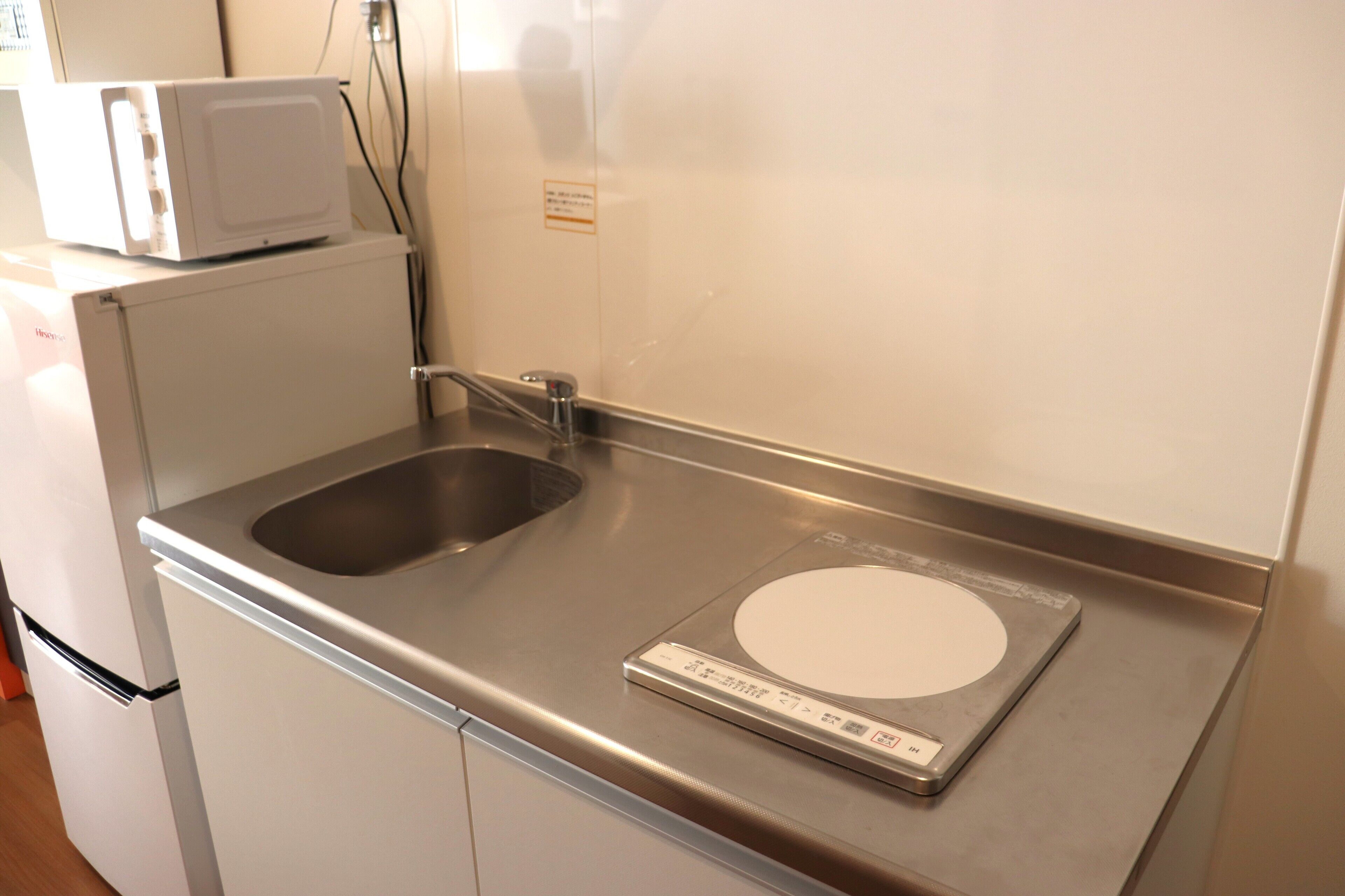 Una cocina con un lavamanos de acero inoxidable, un microondas y una balanza digital.
