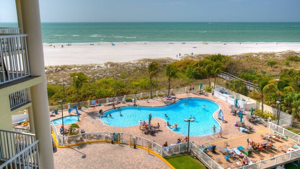 A pool area with multiple swimming pools, a beach in the background, and a view of the ocean. - Family Vacay-Beach Days, Pool Time, Hot Tub, Spectacular Views. Beachfront Pools and Bar, Cafe, Gym (Treasure Island)