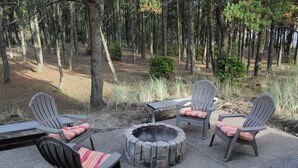 Ein Sitzbereich im Freien mit Adirondack-Stühlen und einem Feuerkorb.