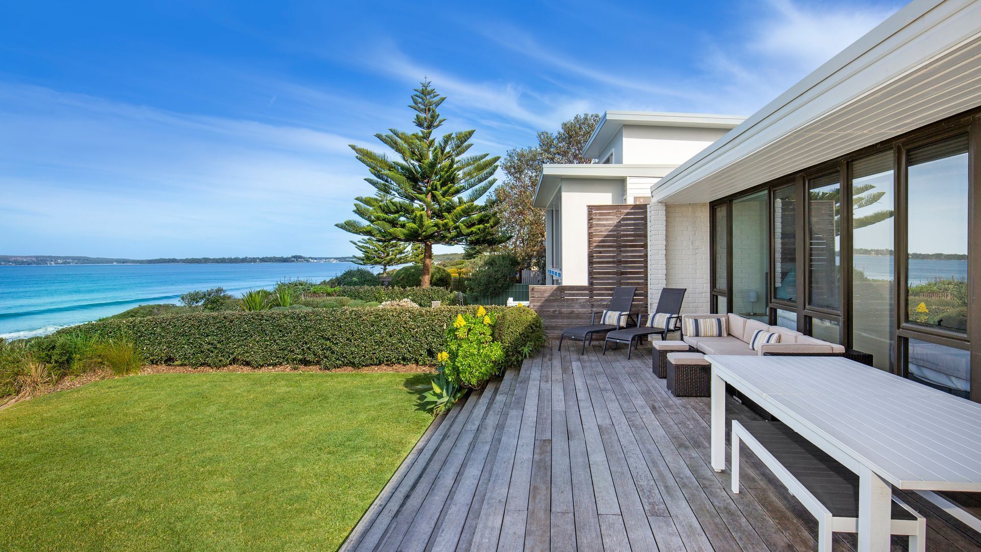 A deck with outdoor furniture overlooking a coastal view.