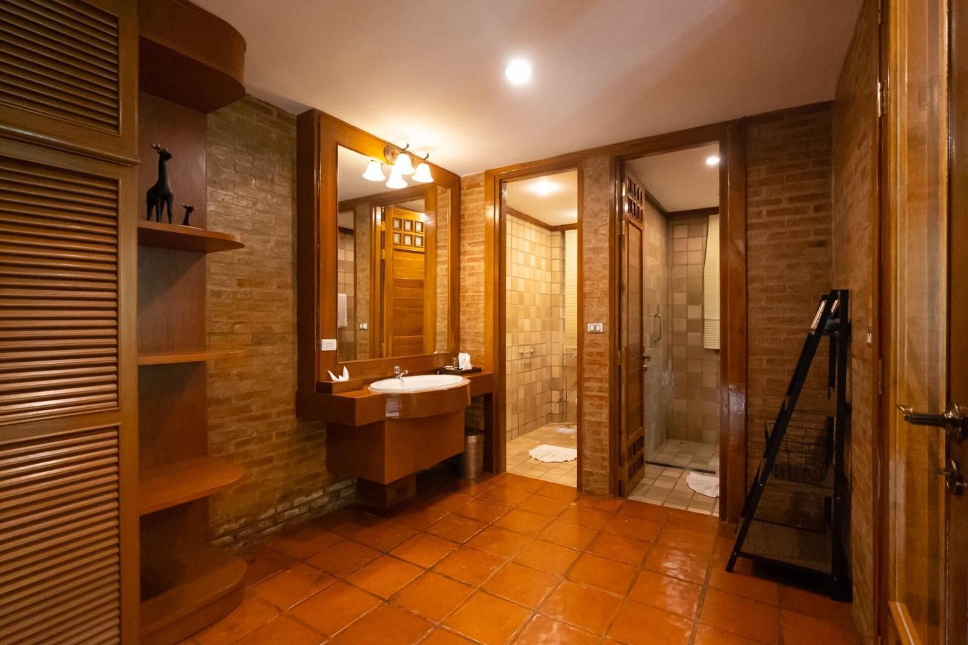 A bathroom with a wooden vanity, a large mirror, a shower area, and a ladder.