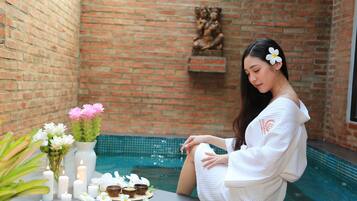 A person sitting by a pool with candles and flowers on a table.