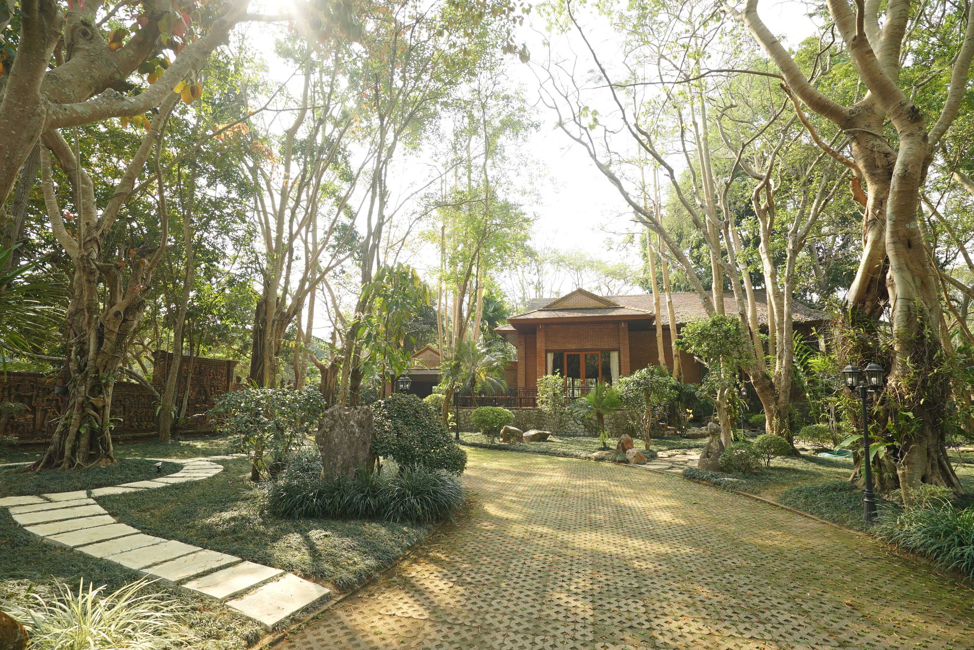 A garden pathway leading to a building with a tiled roof and brick walls.