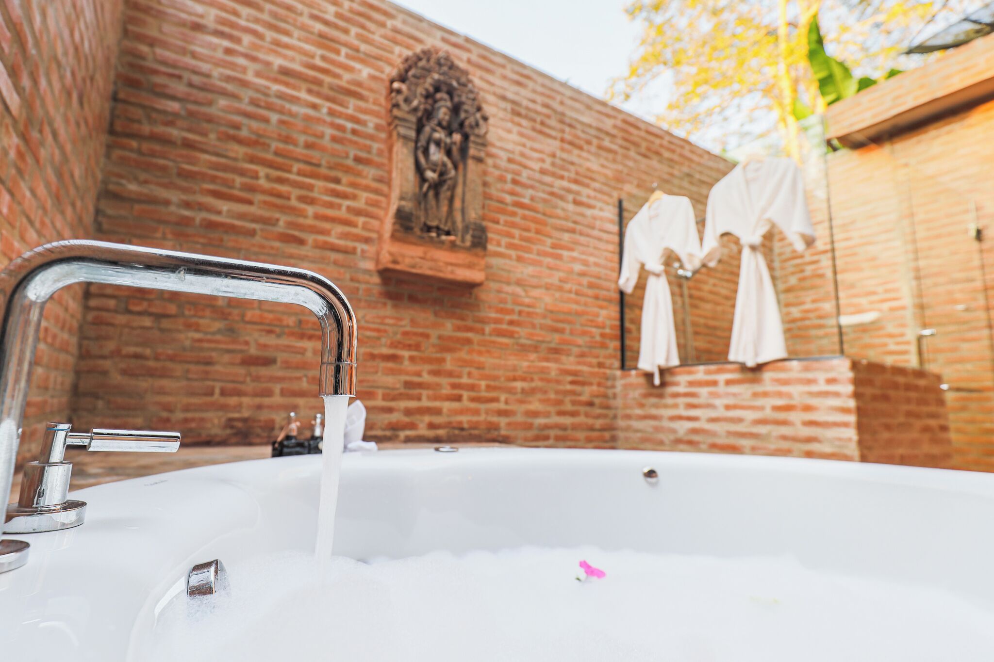 A bathroom with a bathtub, a faucet, and a brick wall.
