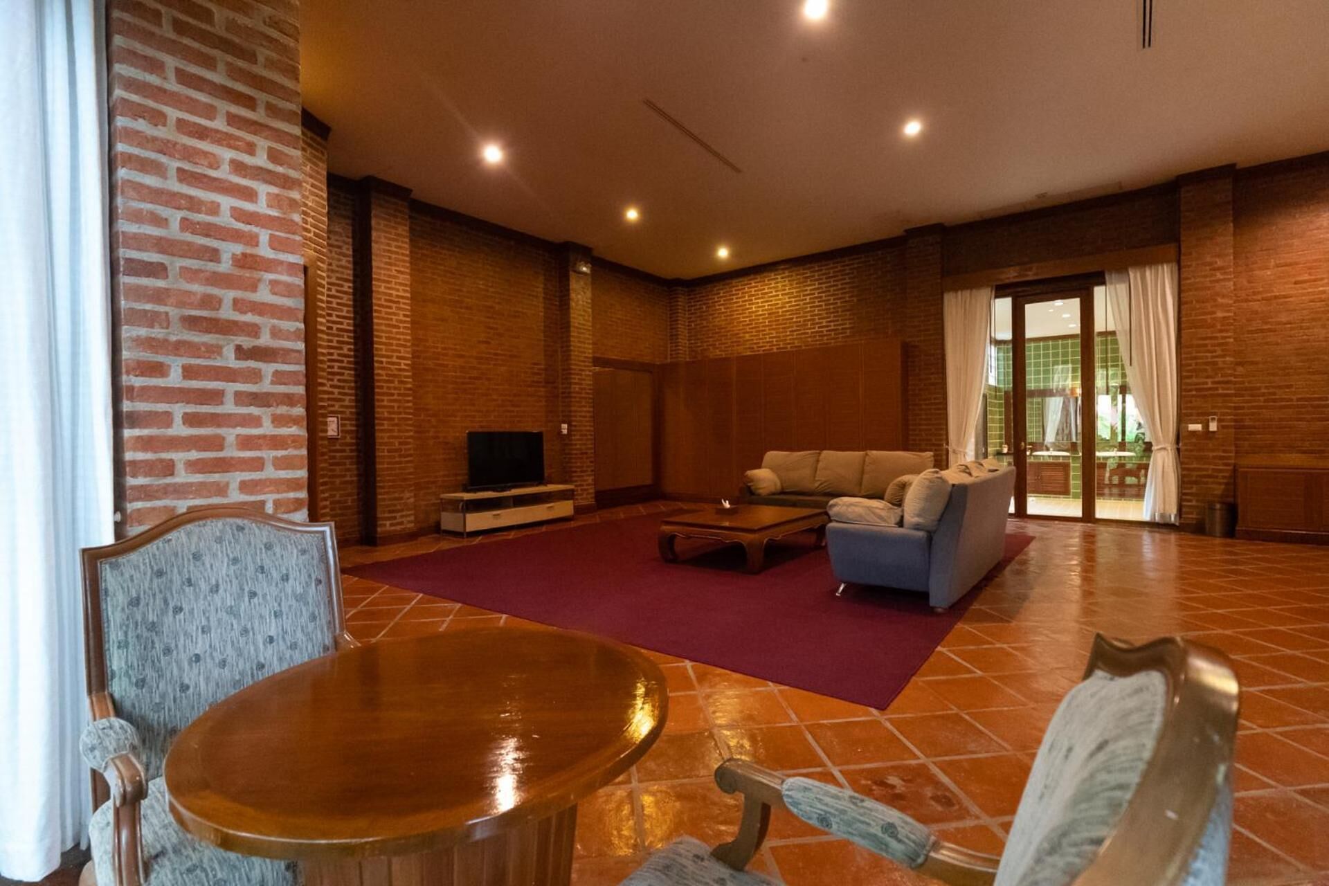 Uma sala de estar espaçosa com parede de tijolos, televisão, sofá e mesa de centro.