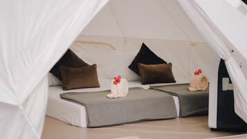 Una carpa con dos camas, cada una con una almohada y una toalla enrollada.