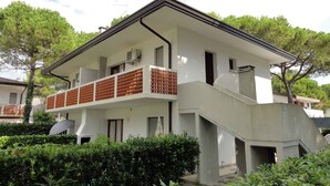 Ein zweistöckiges Gebäude mit Balkon, Treppe und einer kleinen Gartenanlage.