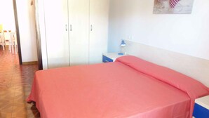 Ein Schlafzimmer mit einem Bett, einem Nachttisch, einem Schreibtisch und einem Kleiderschrank.