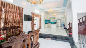 A spacious living area with a wooden sofa, a TV, and a chandelier. - DREAM HOUSE VILLA Vung Tau (Tp. Vũng Tàu)