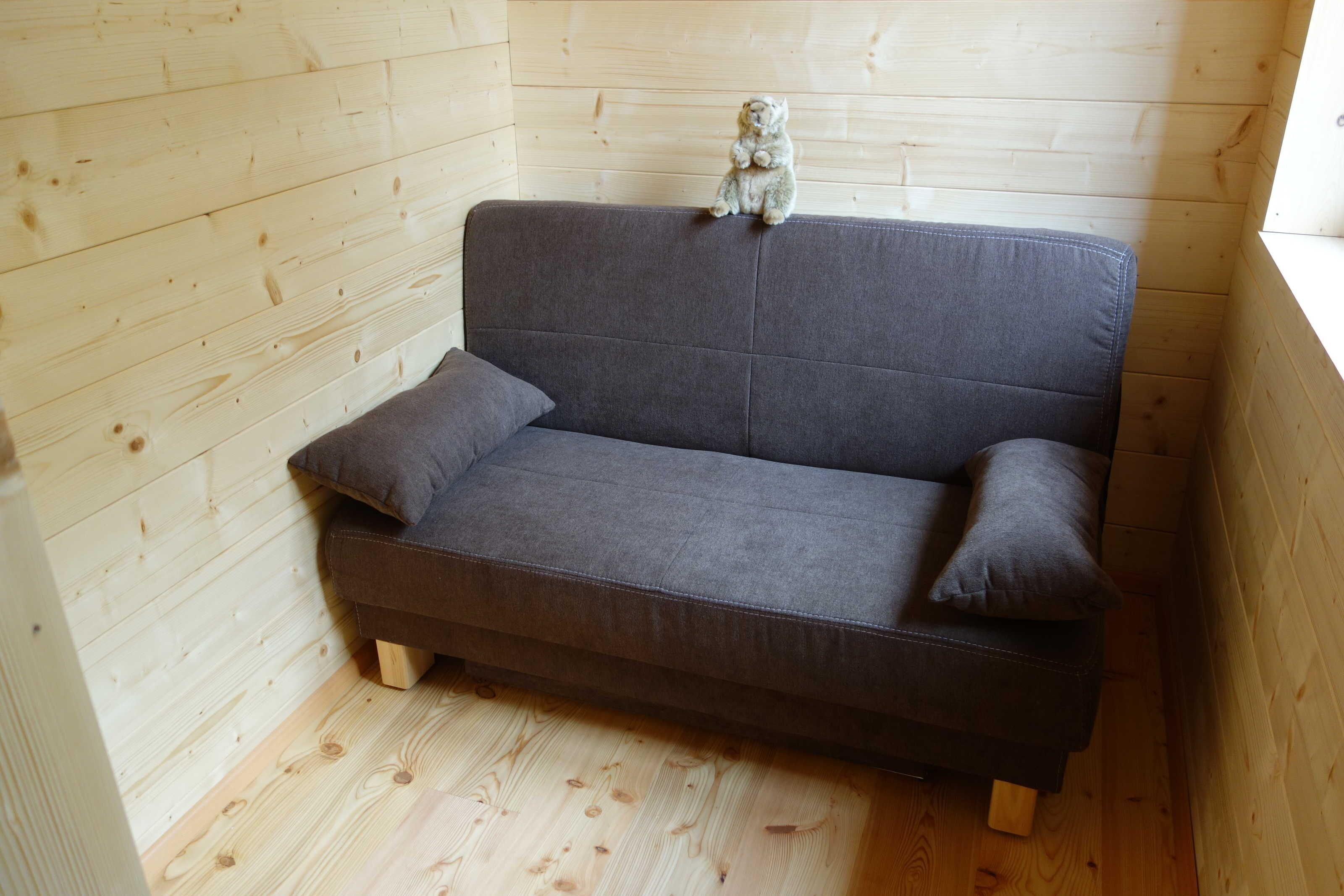 Ein graues Sofa mit Holzbeinen in einem Raum mit Holzwänden und Holzböden.