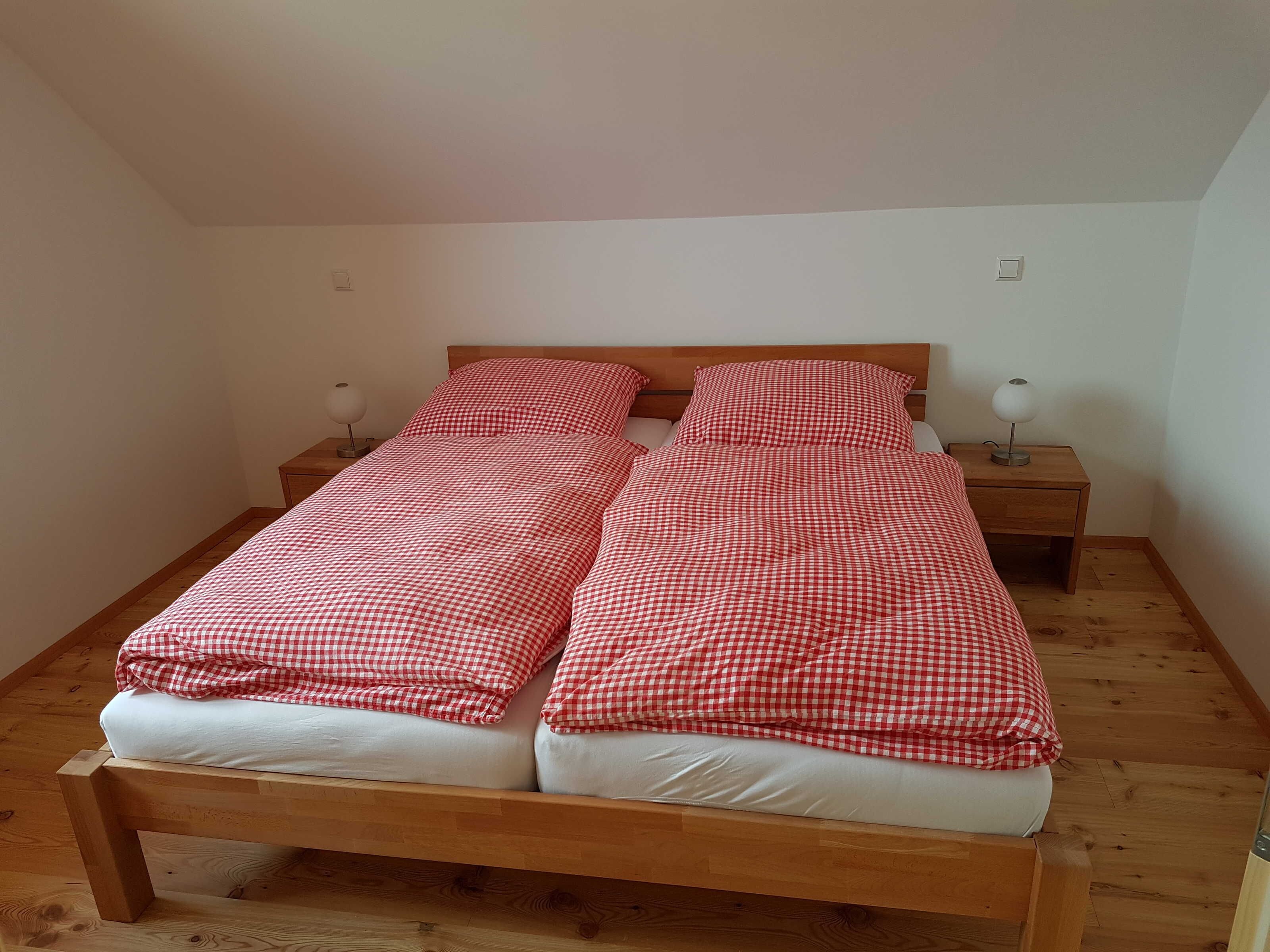Ein Einzelbett mit kariertem Überwurf, zwei Nachttische mit Lampen und ein Holzboden.